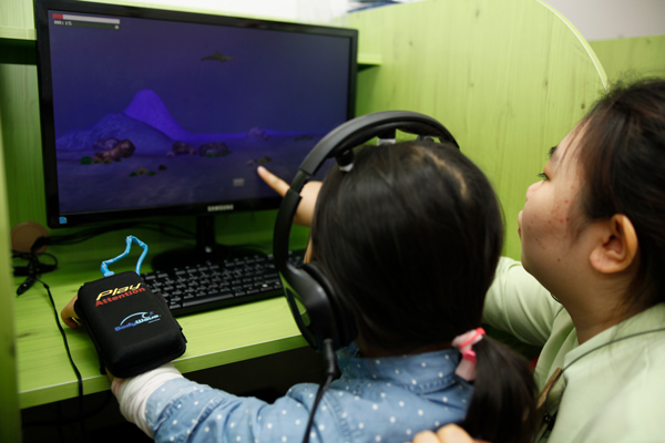 2. 뇌움핏 교육. 치료사가 뇌 모형을 가리키며 아이에게 뇌의 발달 원리를 설명하고 뇌파 기반 집중력 프로그램의 목표를 이해시키는 모습.